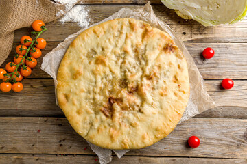 Ossetian pie with cabbage on old wooden table top view