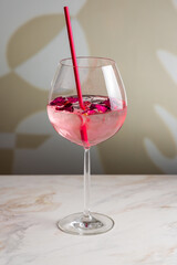 cocktail with roses on a white marble table vertical