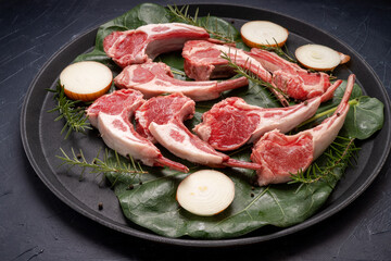 Lamb chops with rosemary and onion in black plate on wooden background, Fresh Raw lamb loin on black Background.