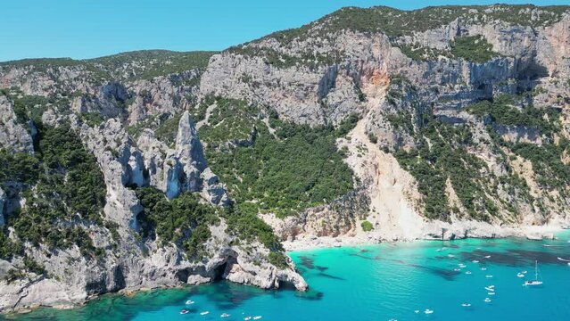Tourist Boats Enjoy Summer Vacation at Cala Goloritze Beach and Rock Formation in Sardinia, Italy - Aerial 4k