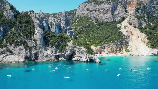 Tourist Boats Relax at Summer Vacation in Cala Goloritze Beach, Sardinia, Italy - Aerial 4k Circling
