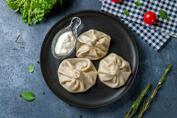 Khinkali with lamb and sour cream top view on black plate