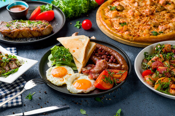 English Breakfast on a plate, pizza with seafood, salad with orange and salmon, steak striploin, salad with duck side view