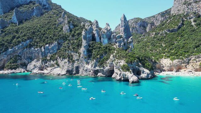 Tourist Boats Relax at Turquoise Blue Sea at Cala Goloritze Beach, Sardinia, Italy - Aerial 4k Circling