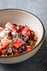 Granola with fresh berries on bowl on grey table vertical macro close up