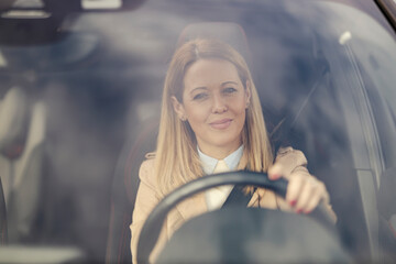 Portrait of a woman looking trough the glass in her car while driving.