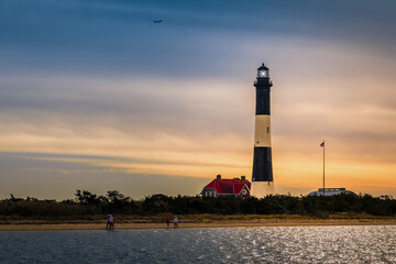 The Fire Island Lighthouse  on the Great South Bay,  Long Island, New York,  with tourists on the beach and ocean water in the foreground