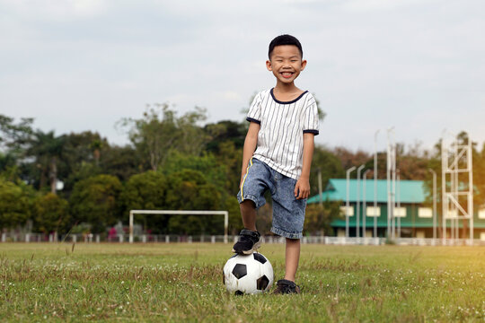 Asian boy stepping on a ball while kicking soccer on the field. soft and selective focus.