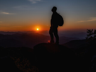 Young Man standing alone in forest outdoor with sunset nature on background Travel Lifestyle and survival concept.