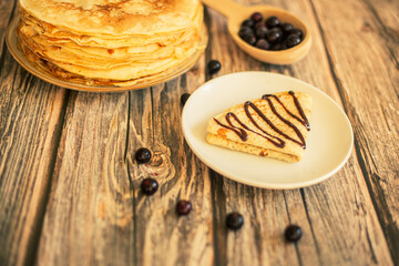 Delicious pancakes with chocolate sauce fresh blueberries on a rustic wooden table. Rustic brown table. 