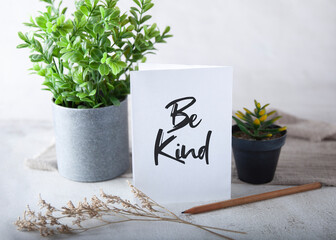 paper with inspirational quote - be kind. along side with potted plants