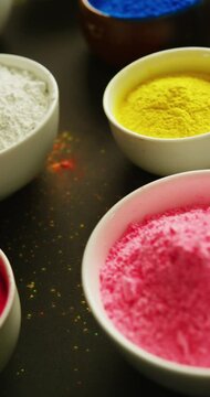 Vertical video of bowls of colourful powders on black background, with copy space