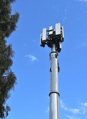 5G mobile cell phone tower against a blue sky.