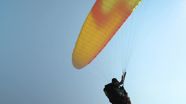Close-up of a paraglider flying over the cameraman's head and landing. Extreme and active leisure. Paragliding is the ultimate adrenaline rush