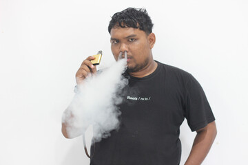 A black man smokes a vape then emits thick white smoke.