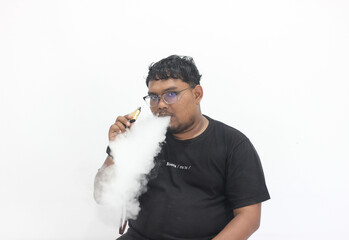 A black man smokes a vape then emits thick white smoke.