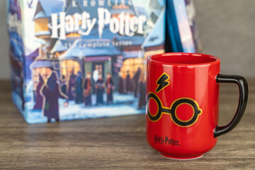Naklejka premium Harry Potter mug and stack of books on background. Harry Potter themed items for fans. 