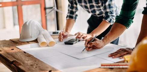Two colleagues discussing data working and tablet, laptop with on on architectural project at construction site
