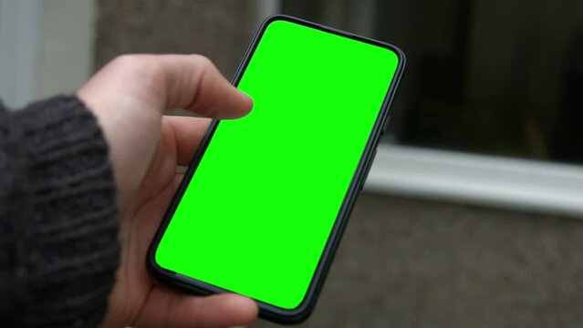 Male Hand Holding Smart Phone Green Screen Replacement with Thumb Swiping Through 4K