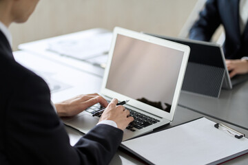 デスクワークでノートパソコンを操作するビジネスパーソン