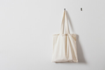White rag bag for groceries. Reusable bag. Vegetarianism, raw food diet, conscious consumption, tissue. Hanging white fabric bag on a hook - Powered by Adobe