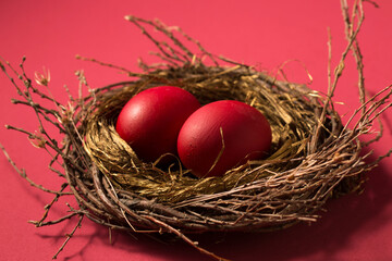 Big red eggs in a nest on a pink background