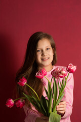 Teenage girl with a bouquet of pink tulips on a pink background