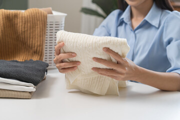Feel softness, asian young woman, female hand holding pile clothing from table, stack folding clean clothes after washing, laundry and dry. Household working at home. Laundry and maid concept.