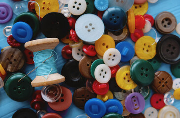 A bunch of colored buttons and a spool of thread and a needle
