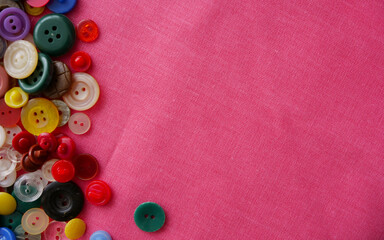 Background of red fabric and colored buttons for clothes of different sizes