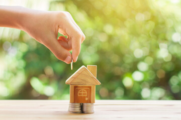 House placed on coins. hand that is coin down the house. Indicates the growth of home and finance....