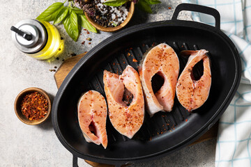 Pieces of fresh salmon fillet with spices on a grill pan. Seafood, culinary background. View from above.