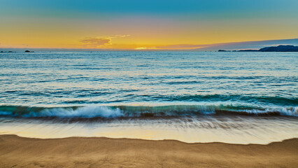 sunset on the beach and the sun is setting on the horizon