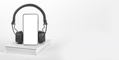 Mobile phone screen mock-up, book and headphones. Smartphone mockup for audio app, audiobook listening. Ads banner, promo background with copy space
