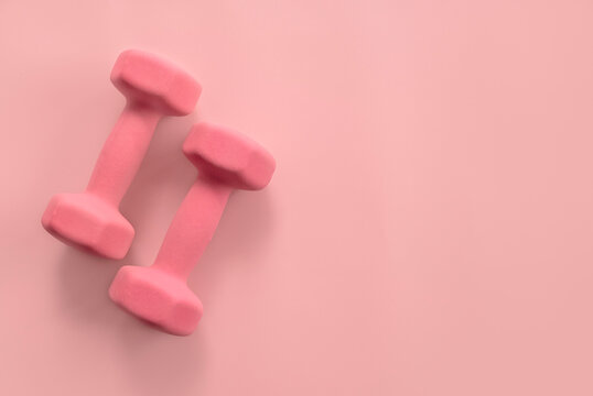 Fitness and healthy sport concept. Pink dumbbell on a pastel pink background. Top view, flat lay, copy space