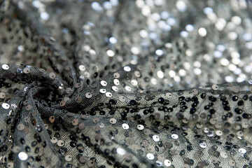 defocused black and silver knitted fabric with sequins and folds texture background	