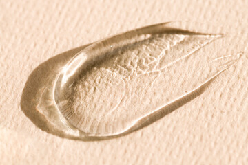 Texture of a transparent cosmetic product, gel, serum on a beige background. Care product sample.