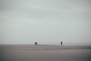 eine einzige kleine Menschengruppe am stürmischen weitläufigen Strand in Dänemark
