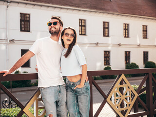 Smiling beautiful woman and her handsome boyfriend. Woman in casual summer jeans clothes. Happy cheerful family. Female having fun. Sexy couple posing in the street at sunny day. In sunglasses