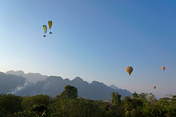 Paragliders and hot air balloons in the sky, Vang Vieng, Laos 