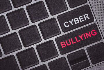 Cyber bullying word on button of laptop. Slander on social media. Bias and racism. Hate Speech in...