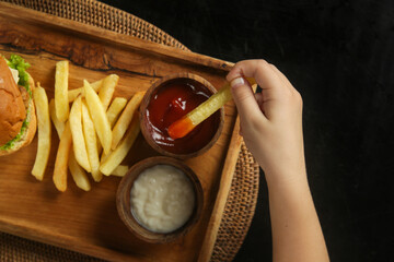 Little girl eating french fries with tomato sauce at the restaurant
