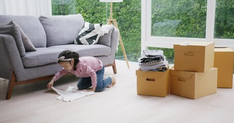 Little small cute girl folding prepare donate box used old clothes give to help poor people at home. Go green asia kid zero waste closet clean clearing reuse textile share to homeless social support.