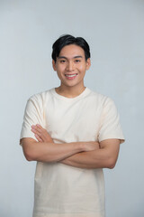 Obraz premium Portrait of a happy young man posing with arms crossed on a white background