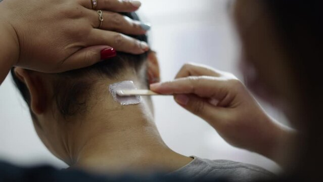 Close up of neck hair removal with wax in a nail saloon