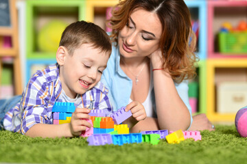 Obraz premium Woman and son playing with plastic blocks on floor