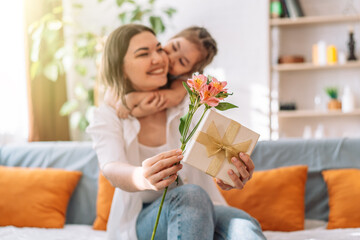 Daughter hugged her mother and gave a gift and flowers. mother's day - obrazy, fototapety, plakaty