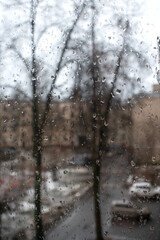 Raindrops on the window pane on a gloomy day. The cityscape outside the window during the winter thaw.