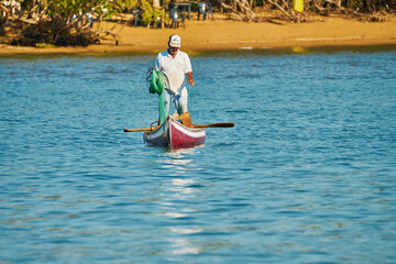 Fototapeta premium fisherman in his canoe using a net to fish in the middle of the sea