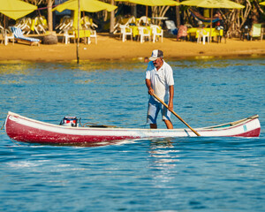 fisherman in his canoe using a net to fish in the middle of the sea